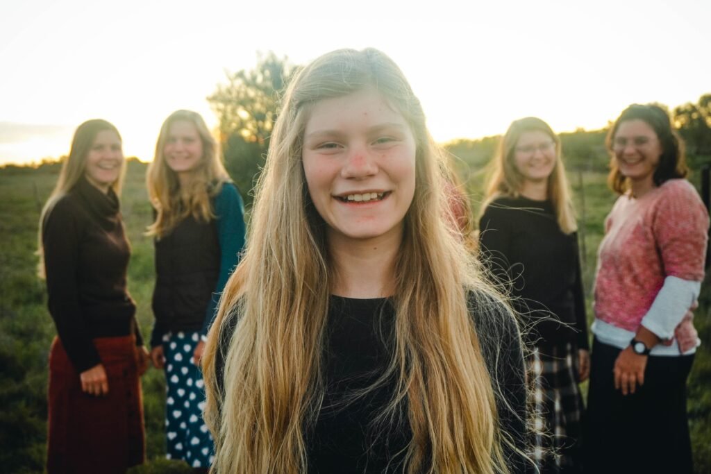 Outdoor group portrait of smiling teenage girl with friends in a field during sunset. pexels-photo-37608890-37608890